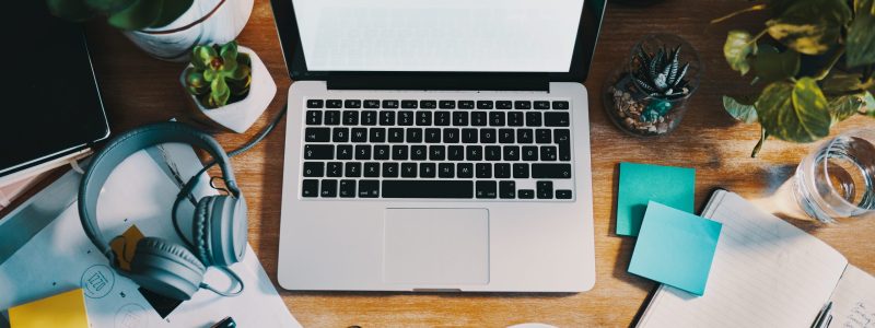 Being organized is essential for getting work done Ordinateur portable sur un bureau avec plusieurs autres accessoires de travail et des plantes.