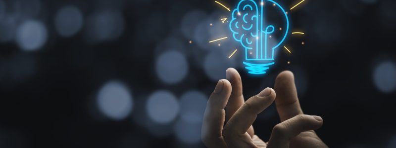 Hand holding drawing virtual lightbulb with brain on bokeh background for creative and smart thinking idea concep Main tenant un globe lumineux ayant la moitié gauche de celle-ci représentant un cerveau.
